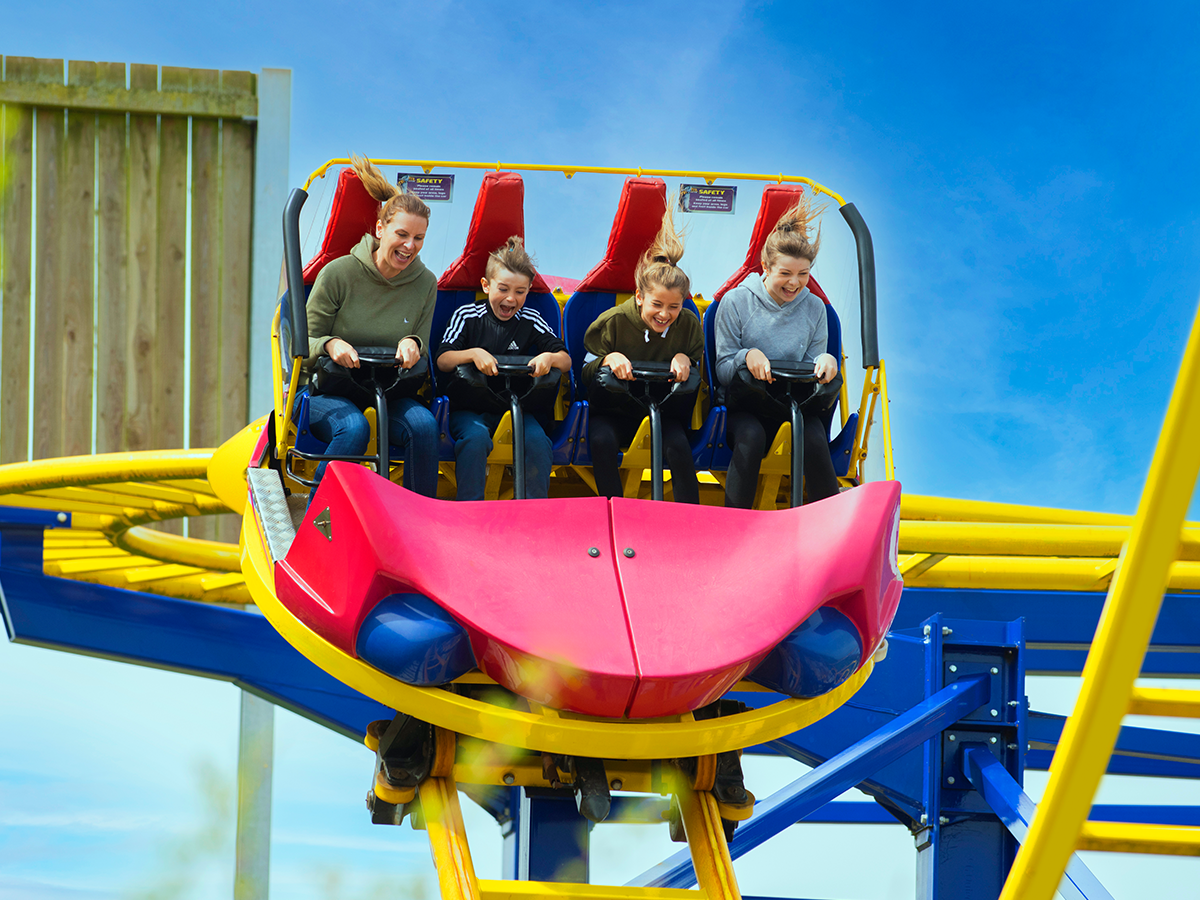 An image of a family on a spinning cart style rollercoaster with yellow tracks 