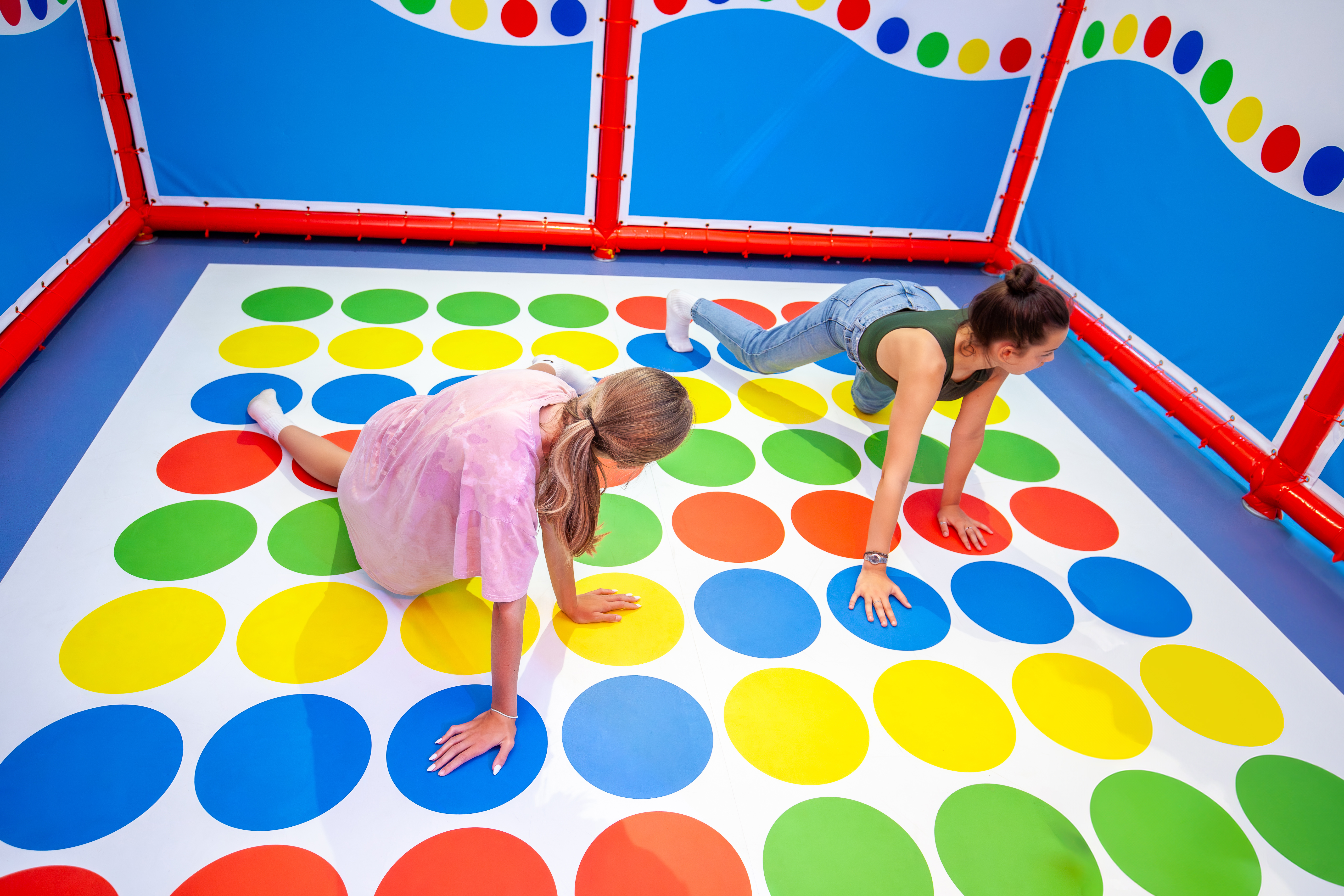 An image of two girls playing a game of giant twister in an indoor play centre 